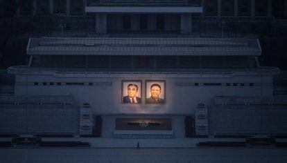 Homem passeia sob os dois grandes retratos de Kim Il-sung (esq.) e Kim Jong-il (dir.) em Pyongyang.