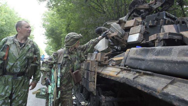 Militantes pró-russos observam os restos carbonizados de um tanque ucraniano perto de Donetsk.