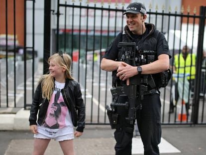 Menina posa com um policial antes do show de Ariana Grande em Manchester, neste domingo.