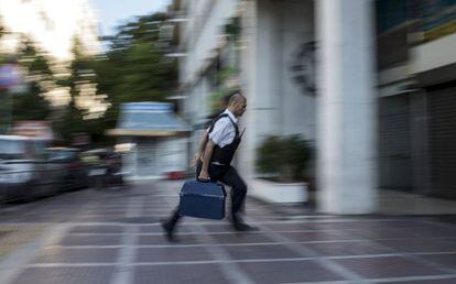 Segurança leva dinheiro a uma sucursal bancária em Atenas.