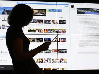 Usuária consulta um tablet em frente a uma tela com a página do Youtube.