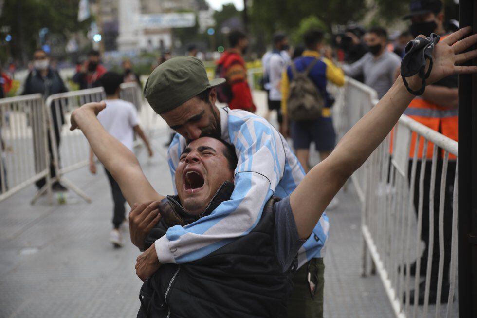 Homens se abraçam em Buenos Aires para se consolar pela morte de Diego Maradona.