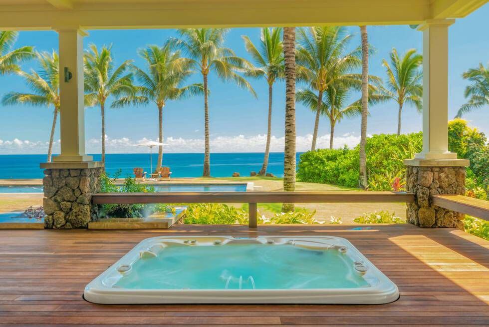 Um dos maiores luxos da casa é a banheira de hidromassagem ao ar livre, com vista para as palmeiras e o mar.
