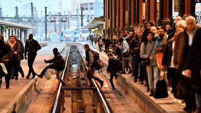 Passageiros cruzam as vias do trem em uma estação de Paris (França).