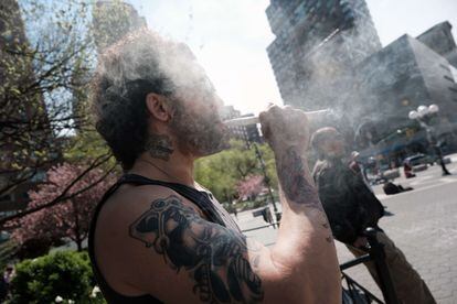 Um homem fuma em Nova York, em 20 de abril, junto a uma banca do Joints For Jabs.