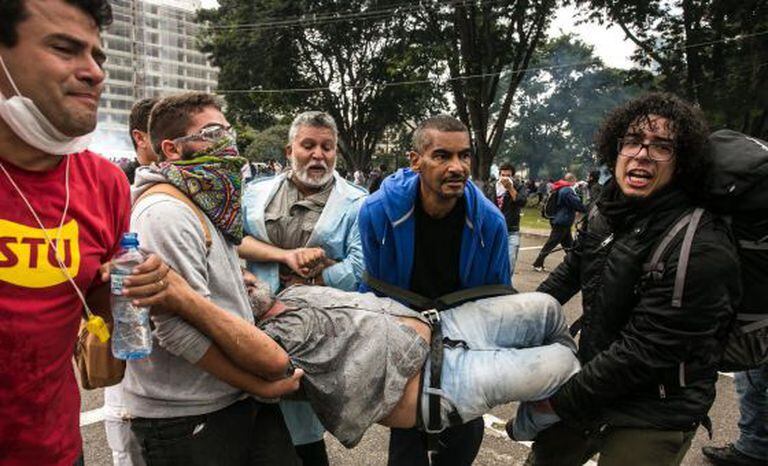 Manifestante é carregado por colegas durante protesto.
