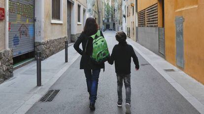 Uma mãe carrega a mochila de seu filho a caminho da escola