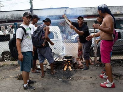 Grupo de venezuelanos assa peixe em churrasqueira improvisada, perto da estação de ônibus de Manaus