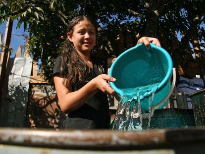 Menina enche um recipiente com água em Honduras.