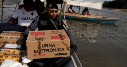 Policial carrega urna eletrônica no Rio Negro, em Manaus.