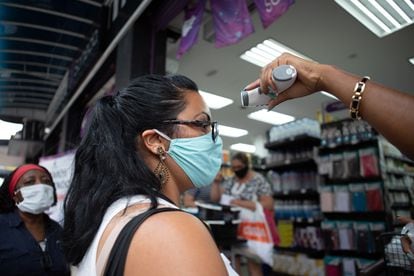 Uma vendedora mede a temperatura de uma cliente antes de ela entrar em uma loja de São Paulo.