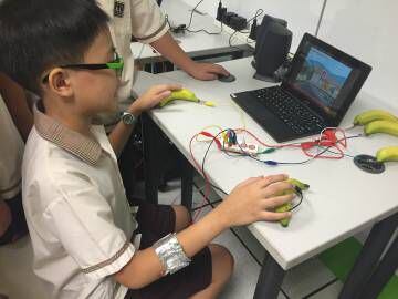 Aluno testa o Pump, o videogame criado por seu colega numa escola pública de Cingapura.