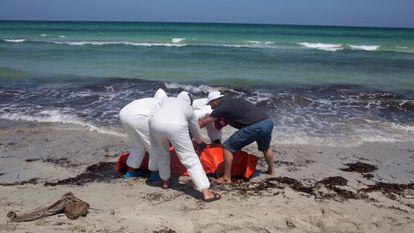 Trabalhadores transladam cadáver de imigrante afogado em frente à costa líbia.