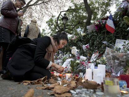 Uma mulher acende uma vela em frente ao Bataclan em Paris.