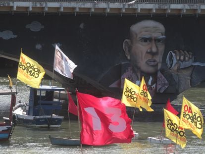 Barcos com bandeiras de políticos na bacia do Pina, ao lado de favela de palafitas.