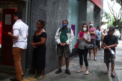 As pessoas esperam na fila para entrar em um banco durante o surto da doença por coronavírus, no bairro de Copacabana, no Rio de Janeiro.