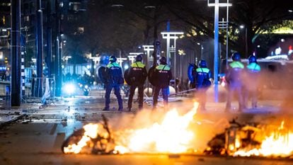 Varios policías se interponen entre los manifestantes y una motocicleta quemada en Róterdam, el viernes.