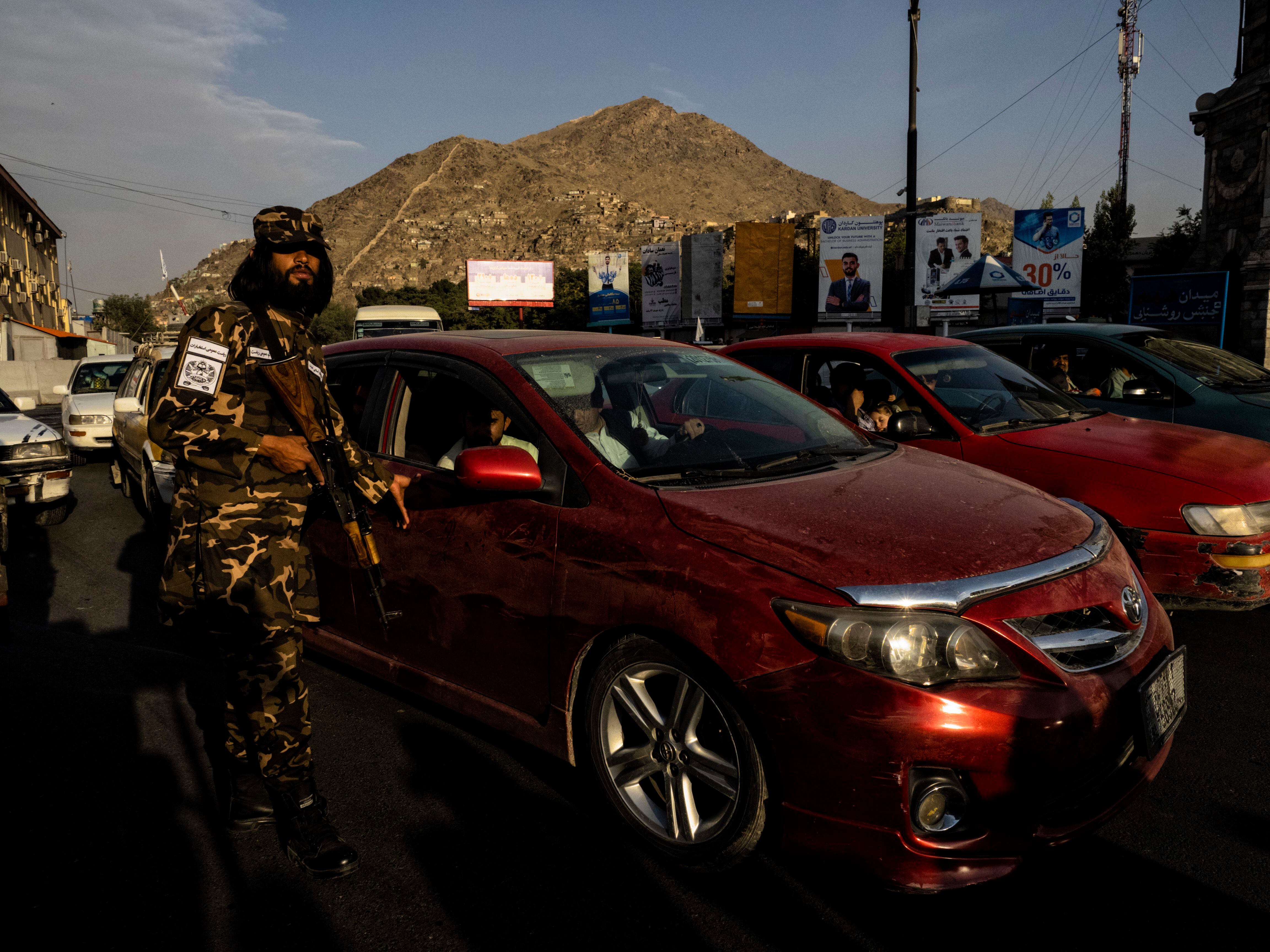 Soldado da milícia controla o tráfego na rotatória onde o Talibã exibe os supostos ladrões.