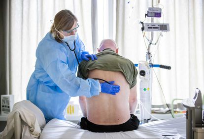 Uma médica ouve os pulmões de um paciente que está se recuperando da admissão na UTI por Covid-19.