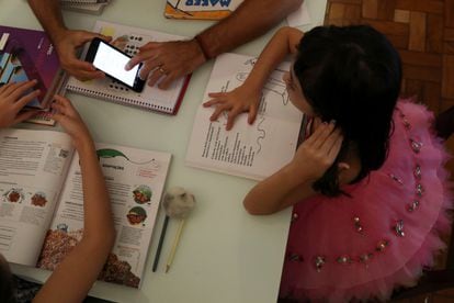 Uma estudante de cinco anos assiste às aulas enviadas pela escola no celular em sua casa, com a ajuda do pai, na cidade paulista de Santo André, em 26 de março, logo após o início da pandemia no Brasil.