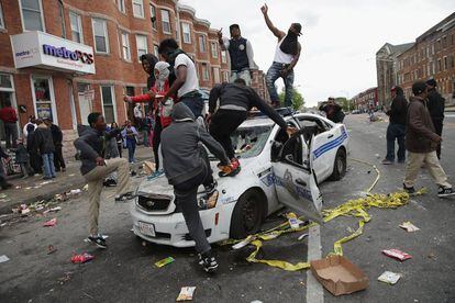 Manifestantes de Baltimore destroem um carro de pol&iacute;cia. 