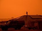 A resident uses a garden hose to wet down the house as high winds push smoke and ash from the Currowan Fire towards Nowra, New South Wales, Australia January 4, 2020. REUTERS/Tracey Nearmy