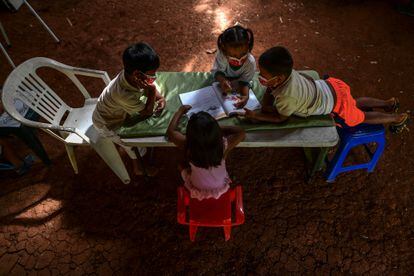 Crianças indígenas embera consultam um livro durante as aulas em sua comunidade em março de 2021 no Panamá.