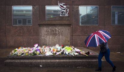 Mulher passa em frente aos ramos de flores deixados em homenagem às vítimas do atentado do sábado na London Bridge.