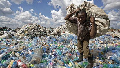 Homem enche uma sacola com plásticos em um lixão nos subúrbios de Nairóbi, Quênia.
