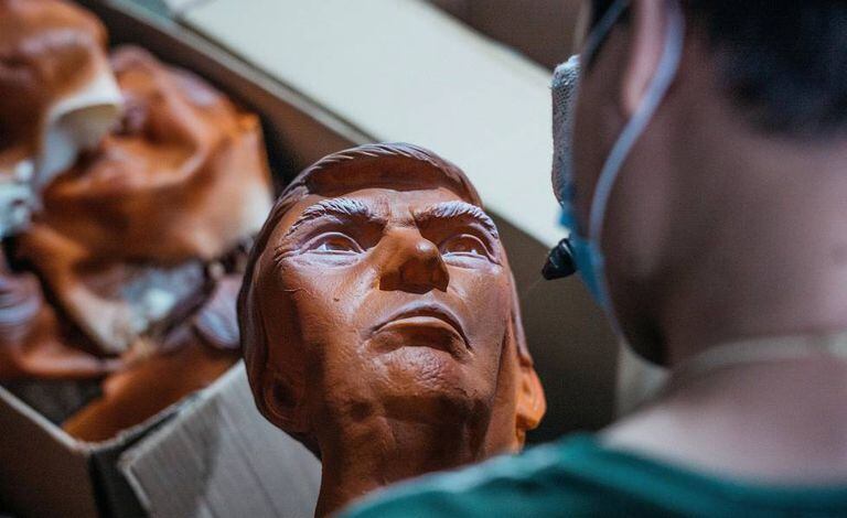 Operário pinta máscara de Trump em fábrica na China.