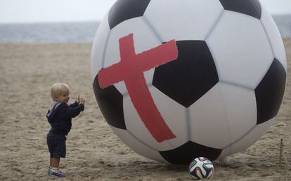 Garoto ao lado de bola gigante usada como protesto contra o Mundial