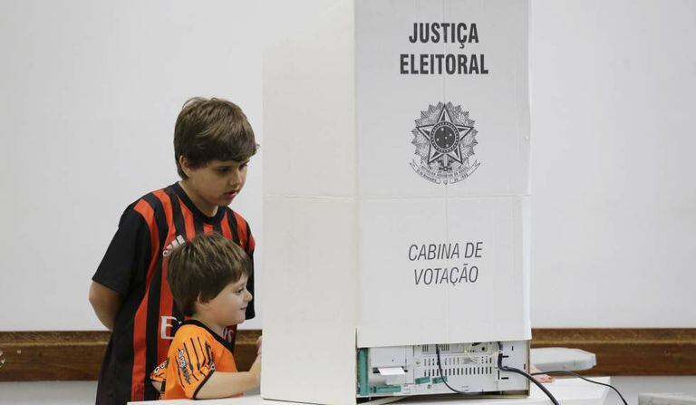 Crianças olham para urna eletrônica durante sessão em colégio eleitoral de São Paulo.