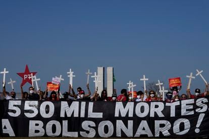 Manifestantes carregam cruzes e faixa que lembra o número de mortos na pandemia em Brasília. 