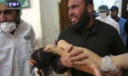 Homem leva menina nos braços ao pronto-socorro na localidade atacada com armas químicas.