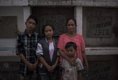 Teresita Yabut e seus filhos diante do túmulo de seu esposo.