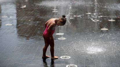 Menina se refresca em chafariz de Madri, durante uma onda de calor.