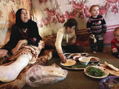Uma mulher síria almoça com seus filhos em campo de refugiados de Saadnayel.