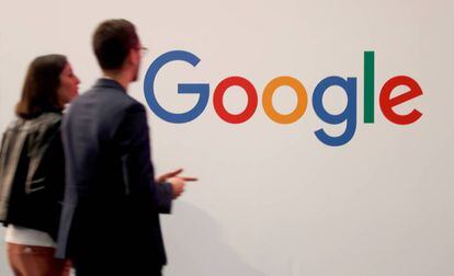 Duas pessoas passam junto ao logotipo do Google em Paris.