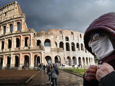 Um homem com máscara diante do Coliseu, em Roma.
