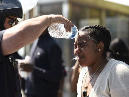 Um policial lava o rosto de uma mulher atingida por spray de pimenta ontem em Baltimore.