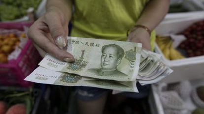 Vendedora mostra notas de yuan em Pequim.