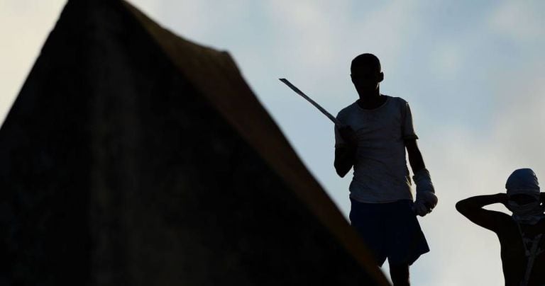 Preso em Alcaçuz segura lança ao lado de colega no teto da cadeia.