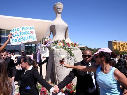 Mulheres protestam depositando flores na est&aacute;tua da Justi&ccedil;a, em Bras&iacute;lia