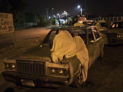 Um homem dorme sobre seu carro enquanto espera por gasolina em Maracaibo.
