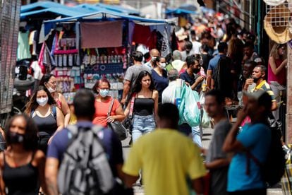 Jovem sem máscara caminha em uma movimentada rua comercial em São Paulo, no momento em que o Brasil vive uma aceleração da pandemia.