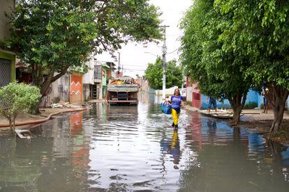 Maria das Graças de Andrade caminha pela rua Tite de Lemos, no Jardim Pantanal, nesta terça-feira. Via estava alagada desde domingo.