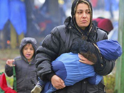 Mulher caminha com seu filho nos braços debaixo da chuva na fronteira entre Croácia e Eslovênia em Trnovec (Croácia).
