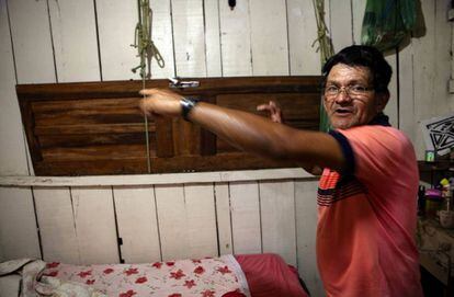 Carlos Alves Moraes, ribeirinho que virou pintor de paredes, mostra a porta suspensa por cordas que usa para erguer seus pertences mais importantes quando a casa alaga.