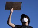 Un manifestante con una mascarilla en la que puede leerse "no puedo respirar" sostiene un cartel que reivindica los 8 minutos y 46 segundos. Foto: Reuters
