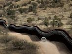 FILE - This March 2, 2019 photo shows a Customs and Border Control agent patrols on the US side of a razor-wire-covered border wall along the Mexico east of Nogales, Ariz. President Joe Biden rushed to send the most ambitious overhaul of the nation's immigration system in a generation to Congress and signed nine executive actions to wipe out some of his predecessor's toughest measures to fortify the U.S.-Mexico border. But a federal court in Texas suspended his 100-day moratorium on deportations. (AP Photo/Charlie Riedel,File)